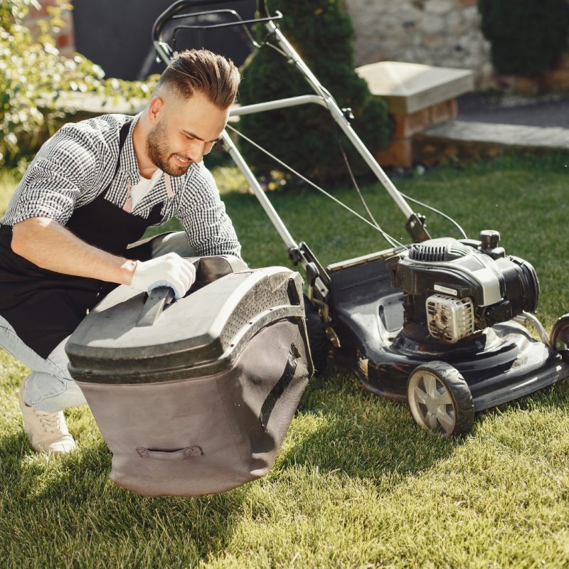 man-cutting-grass-with-lawn-mover-back-yard-male-black-apron-guy-repairs